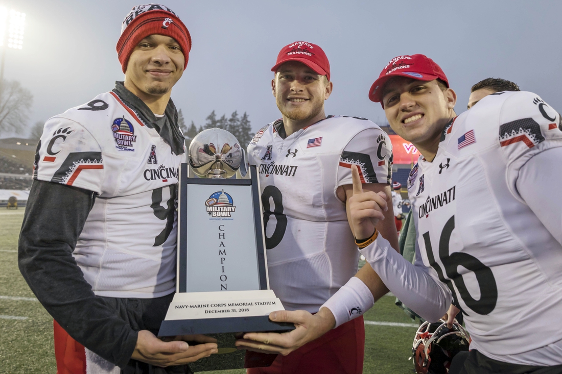Dec 31, 2018; Annapolis, MD, USA; Cincinnati Bearcats quarterback Desmond Ridder (9) and quarterback Hayden Moore (8) and quarterback John Keller (16) pose with the Military Bowl Championship trophy after the game against the Virginia Tech Hokies at Navy-Marine Corps Memorial Stadium. Mandatory Credit: Scott Taetsch-USA TODAY Sports