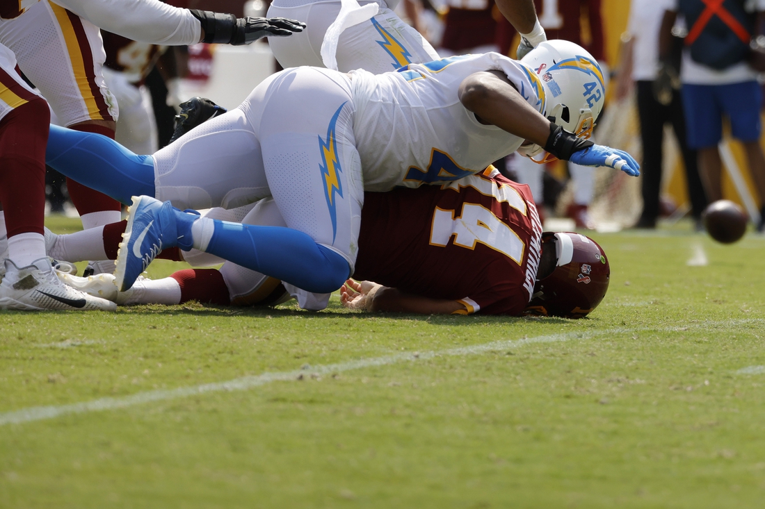 Sep 12, 2021; Landover, Maryland, USA; Washington Football Team quarterback Ryan Fitzpatrick (14) fumbles the ball after being hit by Los Angeles Chargers linebacker Uchenna Nwosu (42) while passing the ball in the second quarter at FedExField. Mandatory Credit: Geoff Burke-USA TODAY Sports