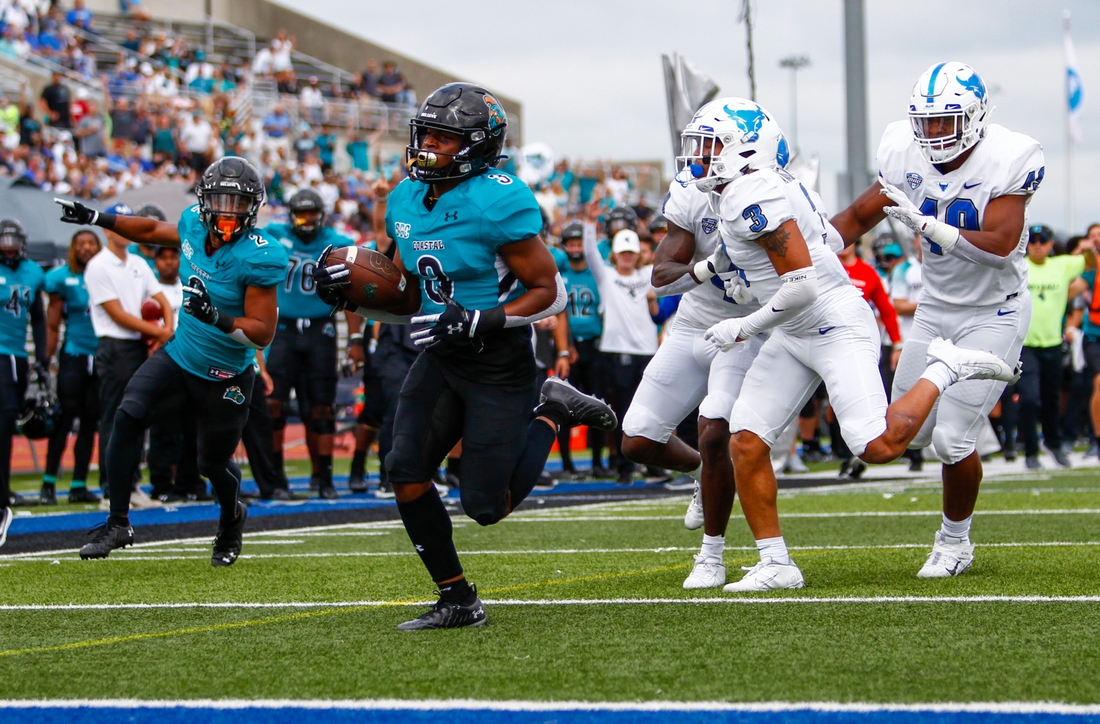 Sep 18, 2021; Buffalo, New York, USA; Coastal Carolina Chanticleers wide receiver Aaron Bedgood (3) turns the ball up field and out runs Buffalo Bulls defensive end Taylor Riggins (49) and cornerback Aapri Washington (3) to score a touchdown giving the Chanticleers an early 7-0 lead during the first quarter of play at UB Stadium. Mandatory Credit: Nicholas LoVerde-USA TODAY Sports