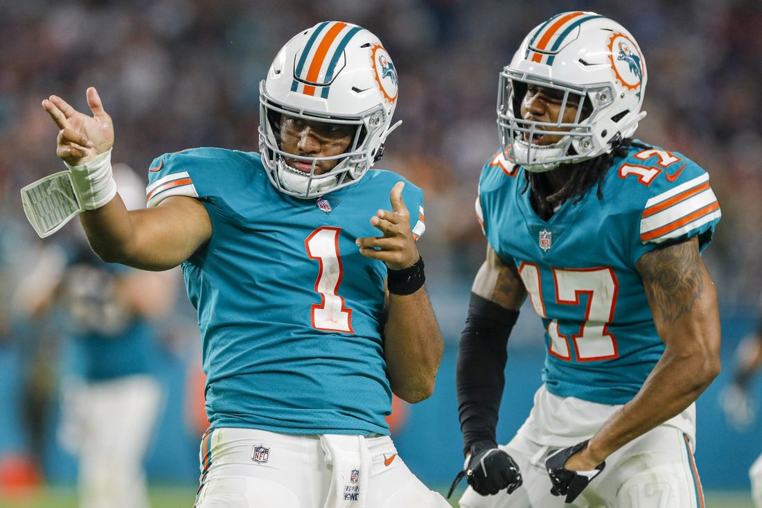 Jan 9, 2022; Miami Gardens, Florida, USA; Miami Dolphins quarterback Tua Tagovailoa (1) reacts with wide receiver Jaylen Waddle (17) after running with the football for a first down against the New England Patriots during the fourth quarter at Hard Rock Stadium. Mandatory Credit: Sam Navarro-USA TODAY Sports