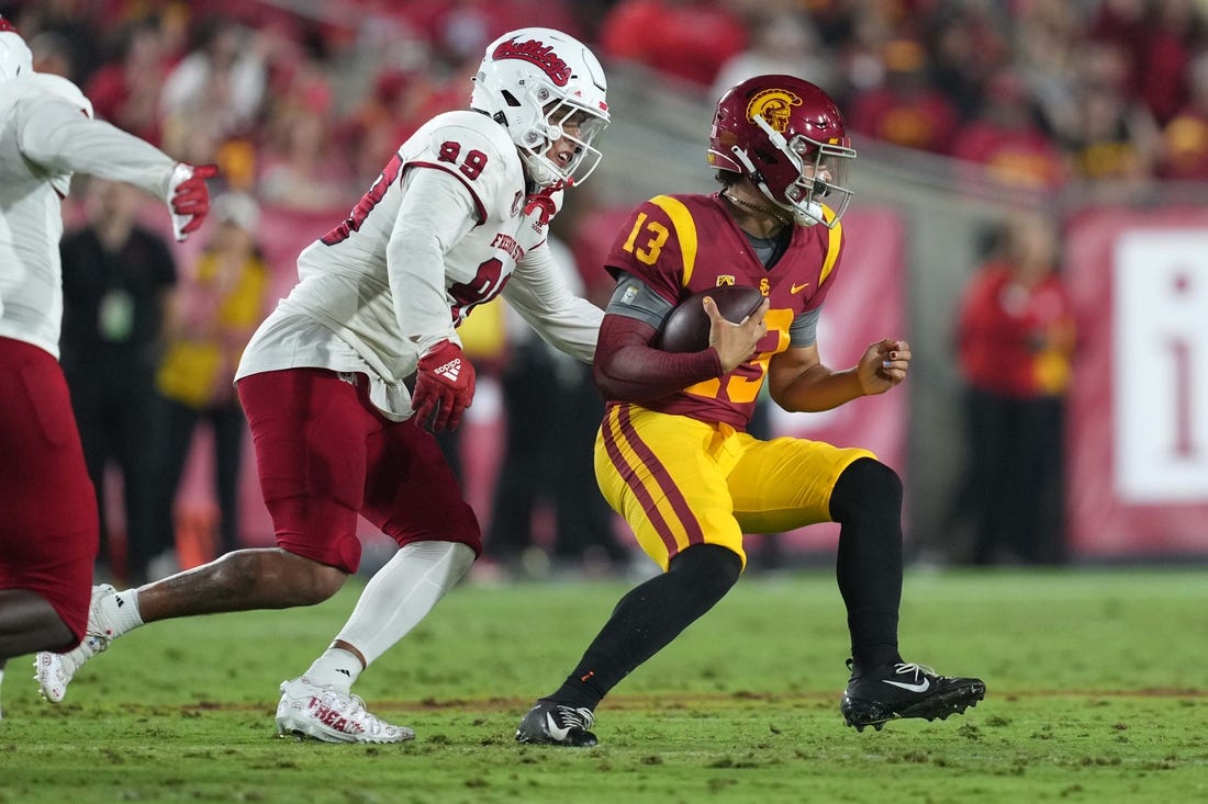 Sep 17, 2022; Los Angeles, California, USA; Southern California Trojans quarterback Caleb Williams (13) is pressured by Fresno State Bulldogs defensive end David Perales (99) in the first half at United Airlines Field at Los Angeles Memorial Coliseum. Mandatory Credit: Kirby Lee-USA TODAY Sports