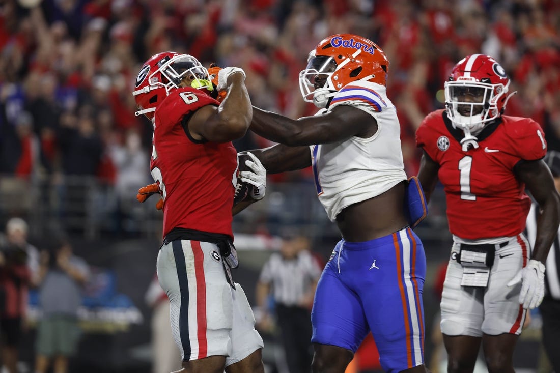 Oct 29, 2022; Jacksonville, Florida, USA; Georgia Bulldogs running back Kenny McIntosh (6) runs the ball in for a touchdown as Florida Gators linebacker Brenton Cox Jr. (1) defends during the second half at TIAA Bank Field. Mandatory Credit: Kim Klement-USA TODAY Sports