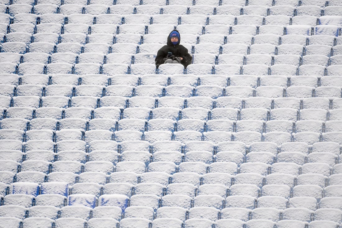 Jan 2, 2022; Orchard Park, New York, USA; A fan sits in the snow covered stands prior to the game between the Atlanta Falcons and the Buffalo Bills at Highmark Stadium. Mandatory Credit: Rich Barnes-USA TODAY Sports