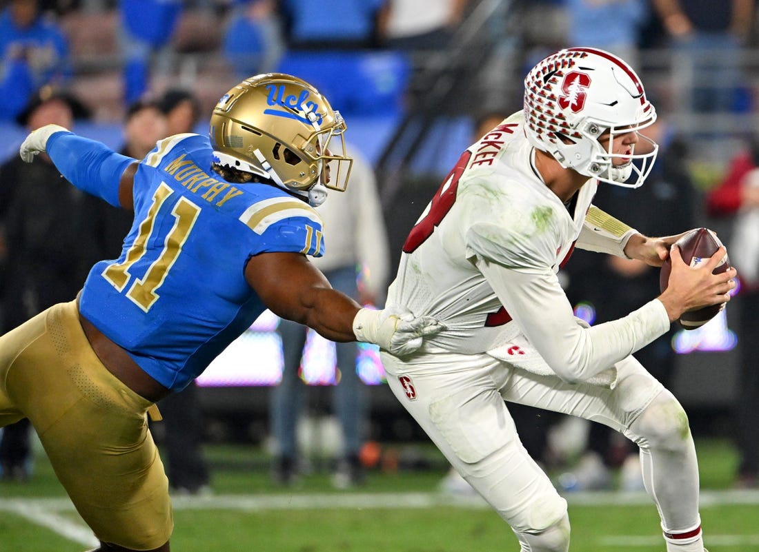 Oct 29, 2022; Pasadena, California, USA;   Stanford Cardinal quarterback Tanner McKee (18) is pressured by UCLA Bruins defensive lineman Gabriel Murphy (11) in the second half at the Rose Bowl. Mandatory Credit: Jayne Kamin-Oncea-USA TODAY Sports