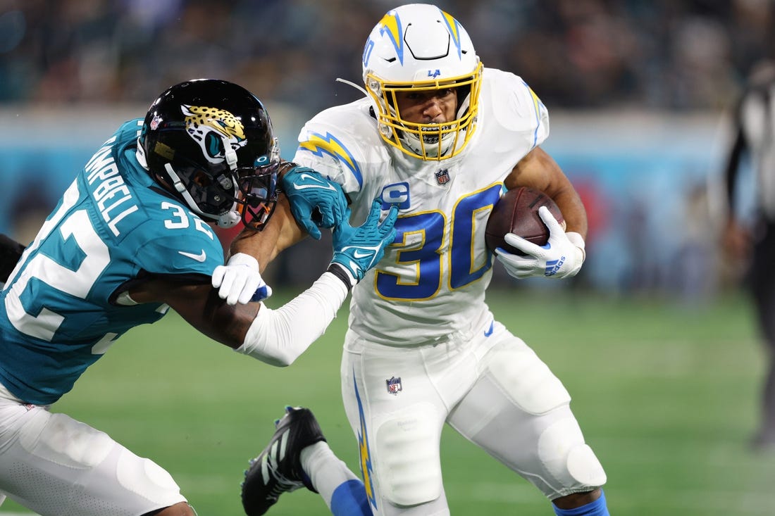 Jan 14, 2023; Jacksonville, Florida, USA; Los Angeles Chargers running back Austin Ekeler (30) is tackled by Jacksonville Jaguars cornerback Tyson Campbell (32) during the first quarter of a wild card game at TIAA Bank Field. Mandatory Credit: Nathan Ray Seebeck-USA TODAY Sports