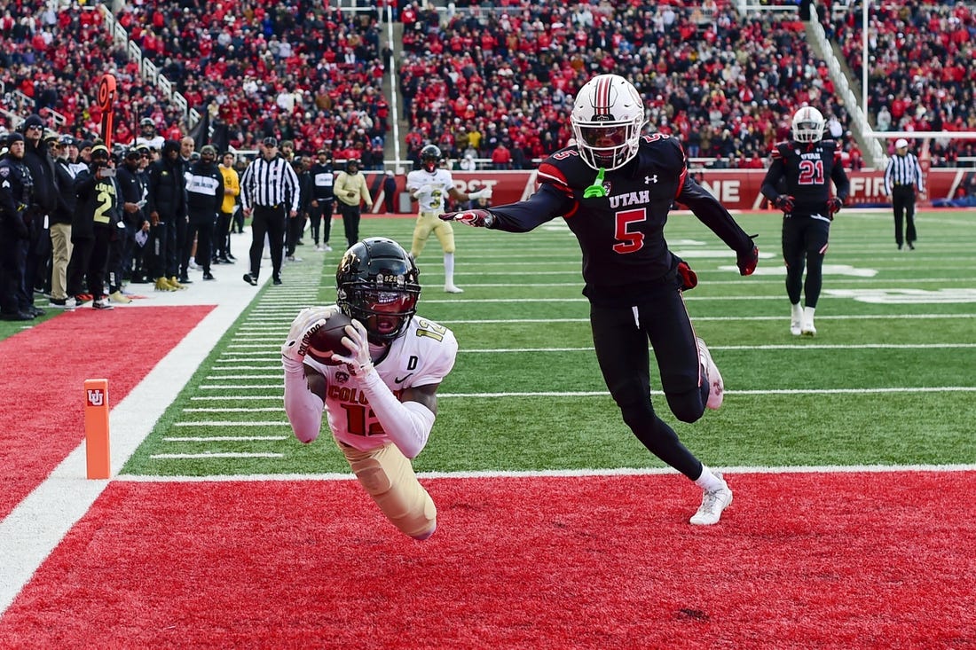 Nov 25, 2023; Salt Lake City, Utah, USA; Colorado Buffaloes athlete Travis Hunter (12) dives for a catch in the end zone in front of Utah Utes cornerback Zemaiah Vaughn (5) at Rice-Eccles Stadium. Mandatory Credit: Christopher Creveling-USA TODAY Sports