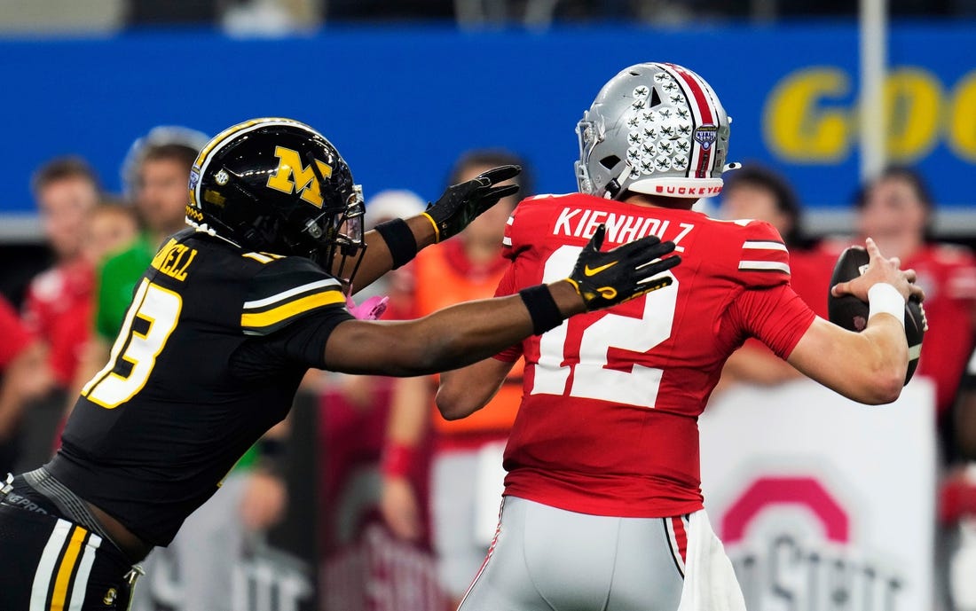 Dec 29, 2023; Arlington, Texas, USA; Ohio State Buckeyes quarterback Lincoln Kienholz (12) almost gets sacked by Missouri Tigers defensive back Daylan Carnell (13) before throwing the ball away in the second quarter during the Goodyear Cotton Bowl Classic at AT&T Stadium.